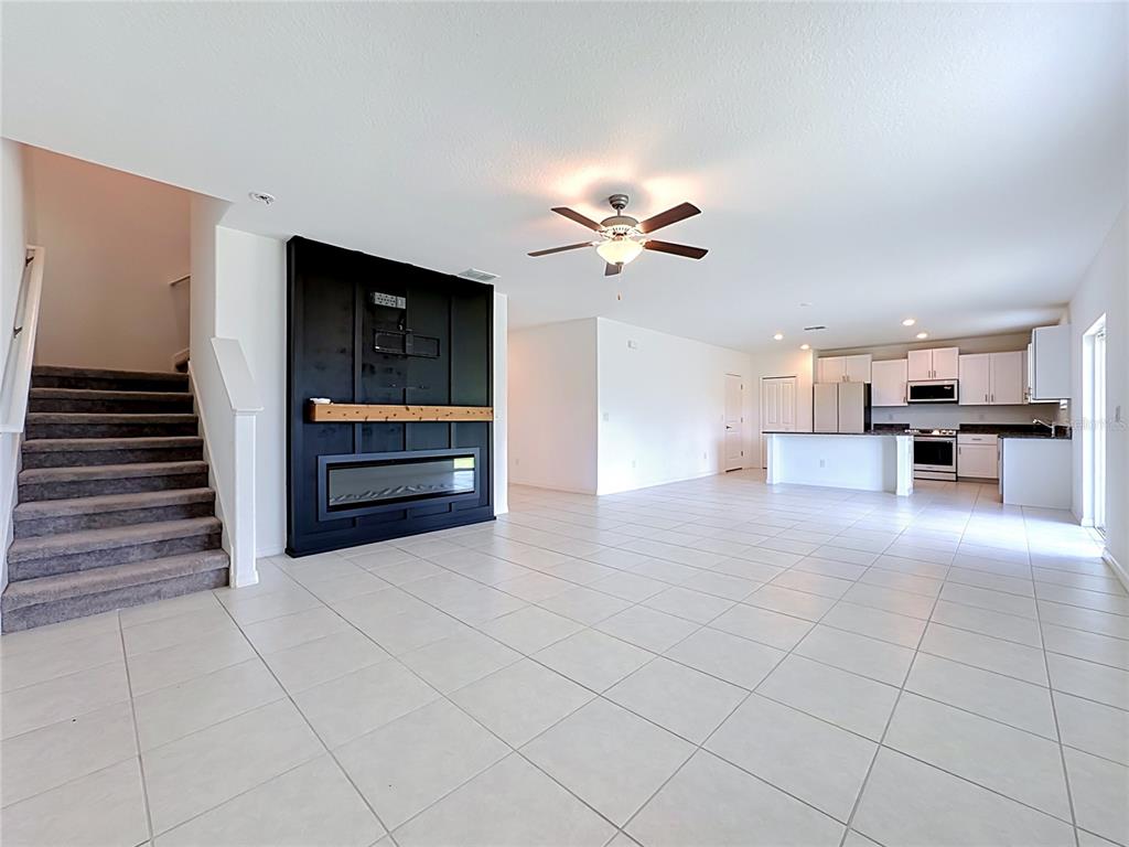 An open-concept living area features a black fireplace wall, tile flooring, and a white kitchen — 2739 RED EGRET DRIVE, BARTOW, FL