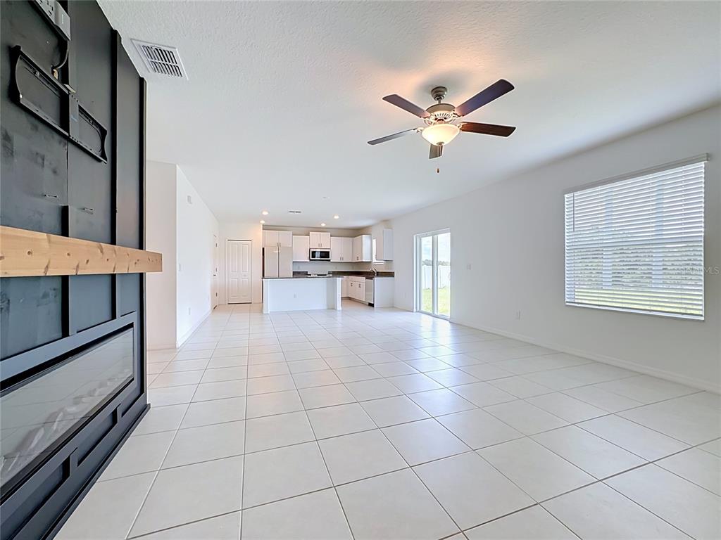 An open-concept living area features white tile flooring, a black fireplace wall, and a kitchen — 2739 RED EGRET DRIVE, BARTOW, FL