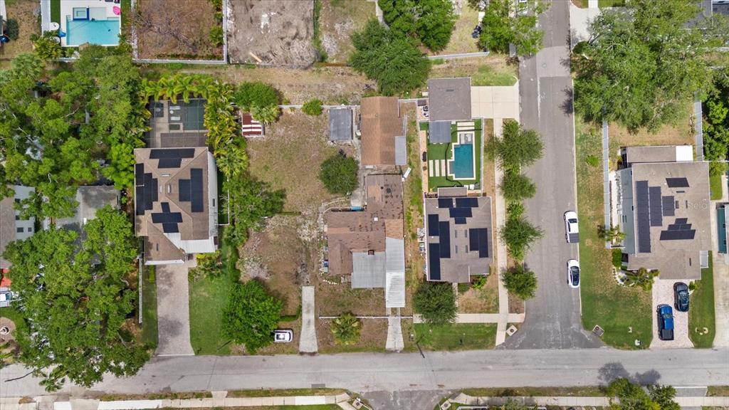 An aerial view shows three residential houses with solar panels and swimming pools along a street — 214 N HABANA AVENUE, TAMPA, FL