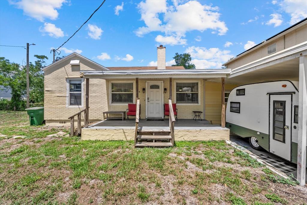 A single-story brick house with a front porch, stairs, and an adjacent parked camper — 214 N HABANA AVENUE, TAMPA, FL
