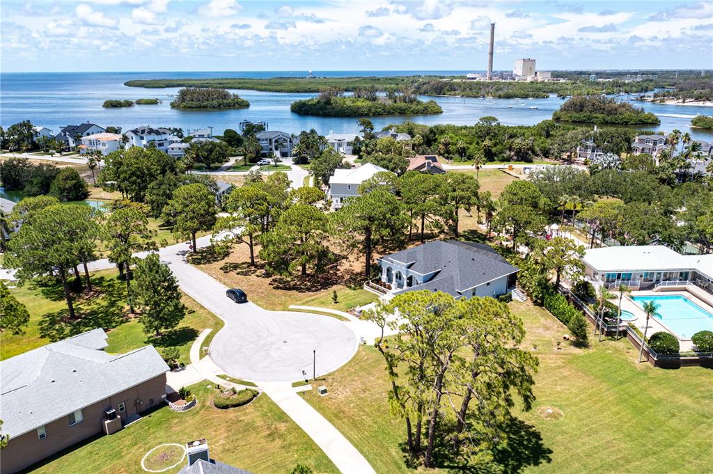 An aerial view shows a residential neighborhood with houses, a cul-de-sac, and a nearby bay — OTTER CT, TARPON SPRINGS, FL