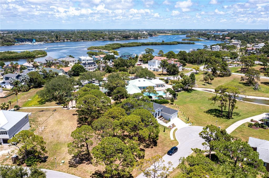 An aerial view shows a residential neighborhood with houses, trees, and a nearby waterway — OTTER CT, TARPON SPRINGS, FL