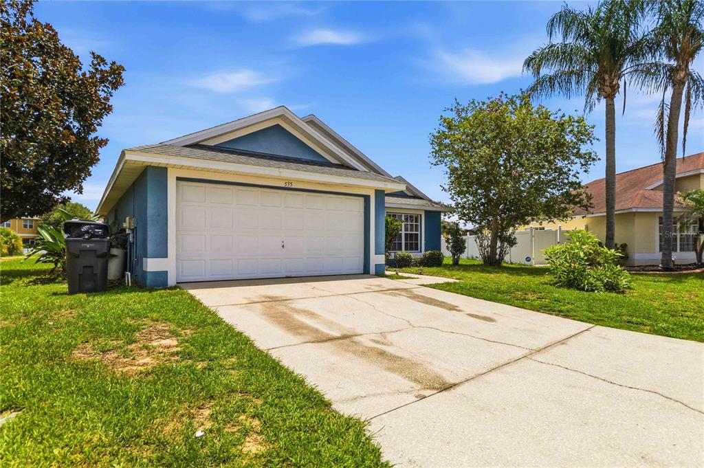 A blue single-story house with a white garage door and a concrete driveway — 535 CORNWALLIS DRIVE, DAVENPORT, FL