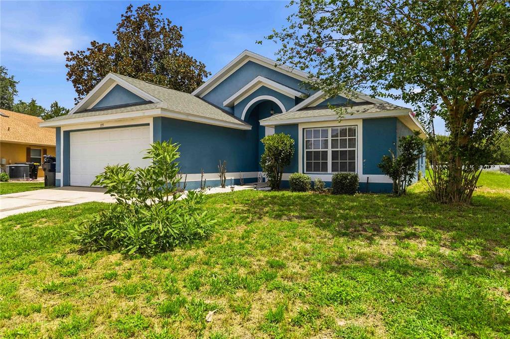 A blue single-story house with a white garage door and a large front yard — 535 CORNWALLIS DRIVE, DAVENPORT, FL