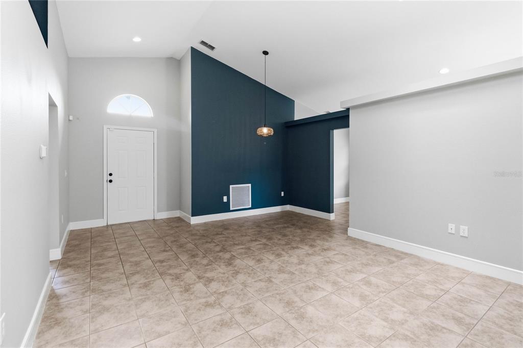 A room with light-colored tile flooring, a vaulted ceiling, and a dark blue accent wall — 535 CORNWALLIS DRIVE, DAVENPORT, FL