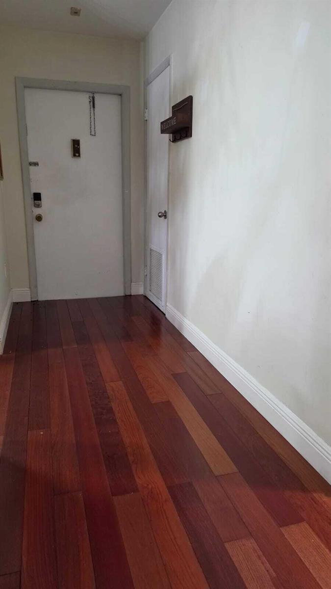An entryway features dark hardwood flooring, a white front door, and a white interior door — 100 Ashbury Road # 206, Hollywood FL 33024, HOLLYWOOD, FL