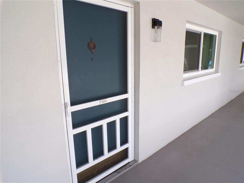A white exterior wall features a teal screen door labeled 304 and a window — 649 S TAMIAMI TRAIL S UNIT 304, VENICE, FL