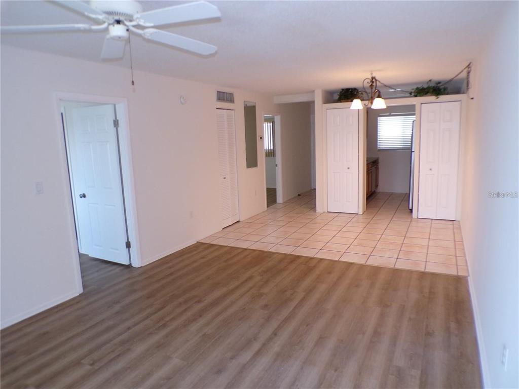 An open-concept living area with wood-look flooring transitions into a tiled kitchen space — 649 S TAMIAMI TRAIL S UNIT 304, VENICE, FL