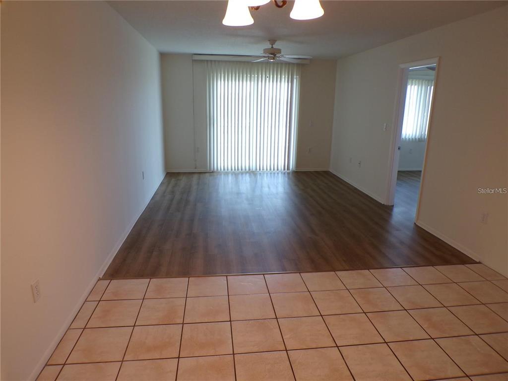 A living room features wood-look flooring, a ceiling fan, and a sliding glass door — 649 S TAMIAMI TRAIL S UNIT 304, VENICE, FL