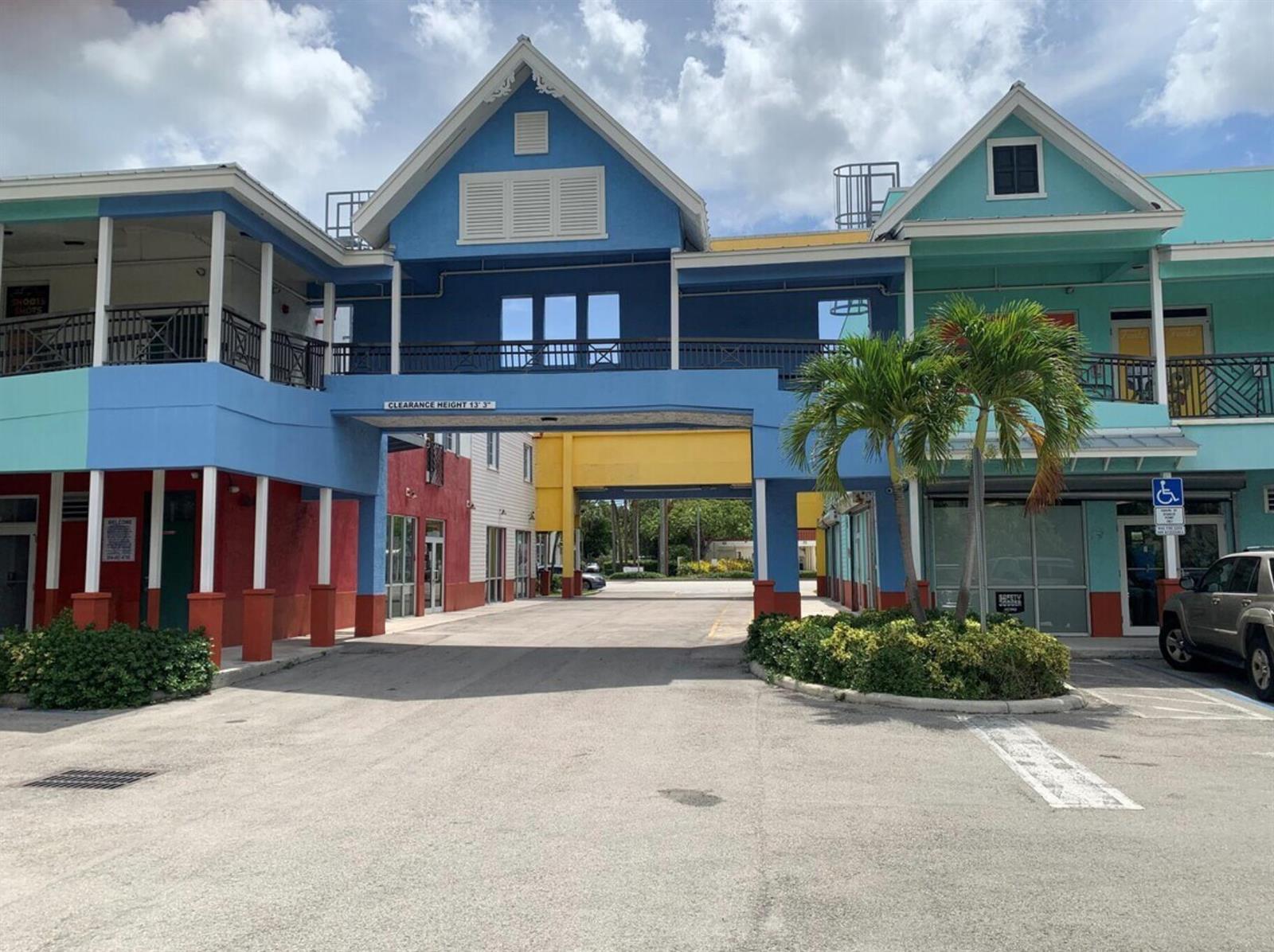 A colorful, multi-story commercial building features a central drive-through archway and a parking lot — 2349 N State Road 7, Lauderhill FL 33313, LAUDERHILL, FL