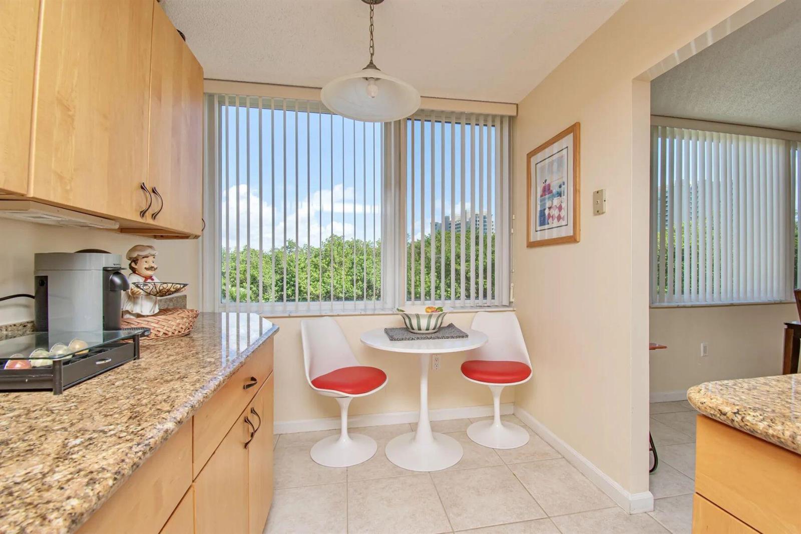 A kitchen breakfast nook features light wood cabinets, granite countertops, and a small round table — 3912 S Ocean Boulevard, Highland Beach FL 33487, HIGHLAND BEACH, FL