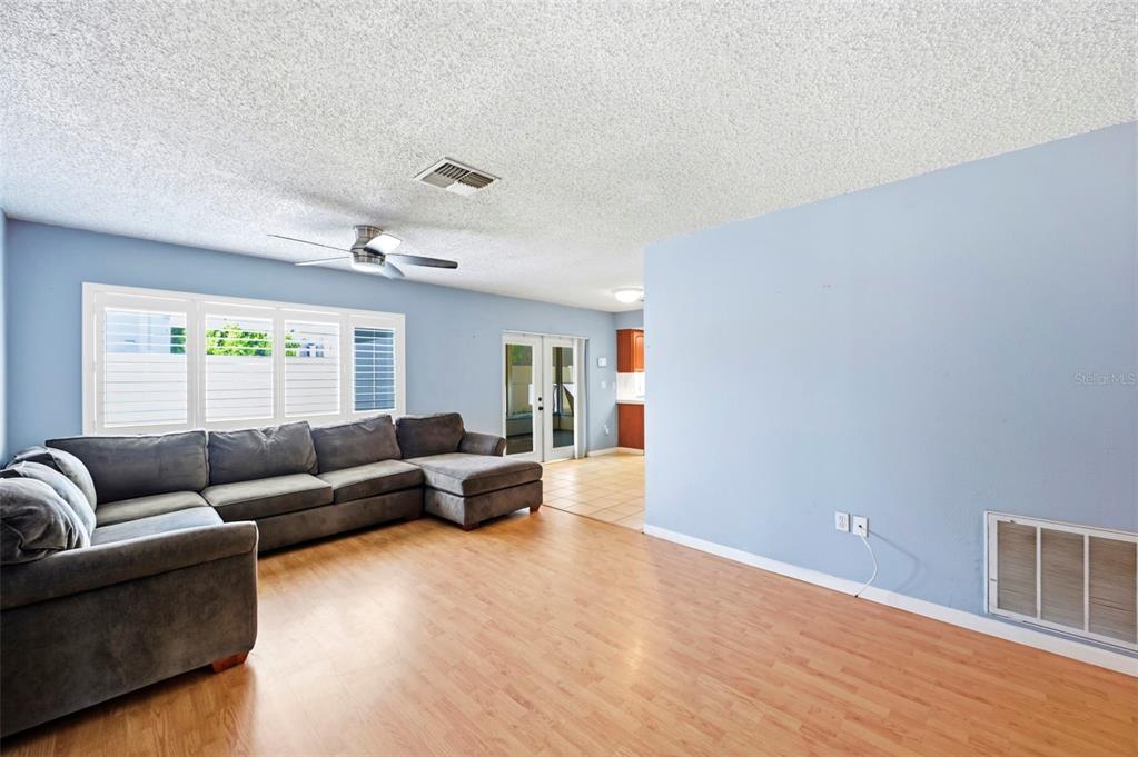 A living room with light blue walls, wood-look flooring, and a large grey sectional sofa — 4314 PINEFIELD AVENUE, HOLIDAY, FL