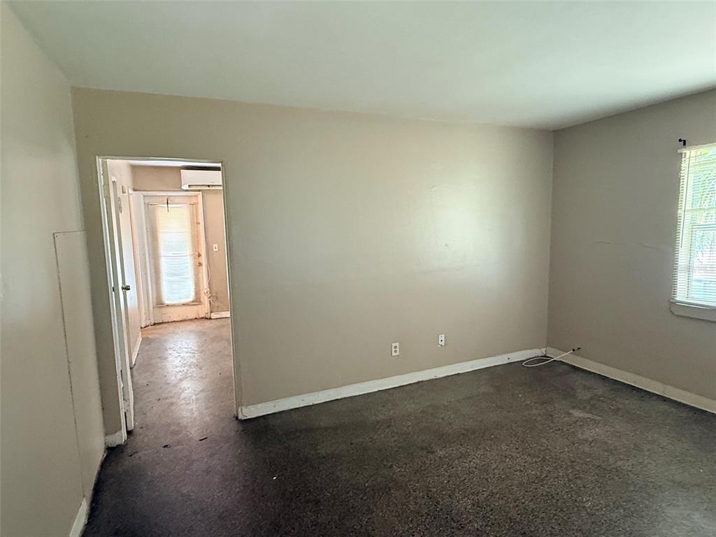 An empty room with beige walls, gray carpeting, and a doorway leading to another area — 1273 S BETTY LANE, CLEARWATER, FL