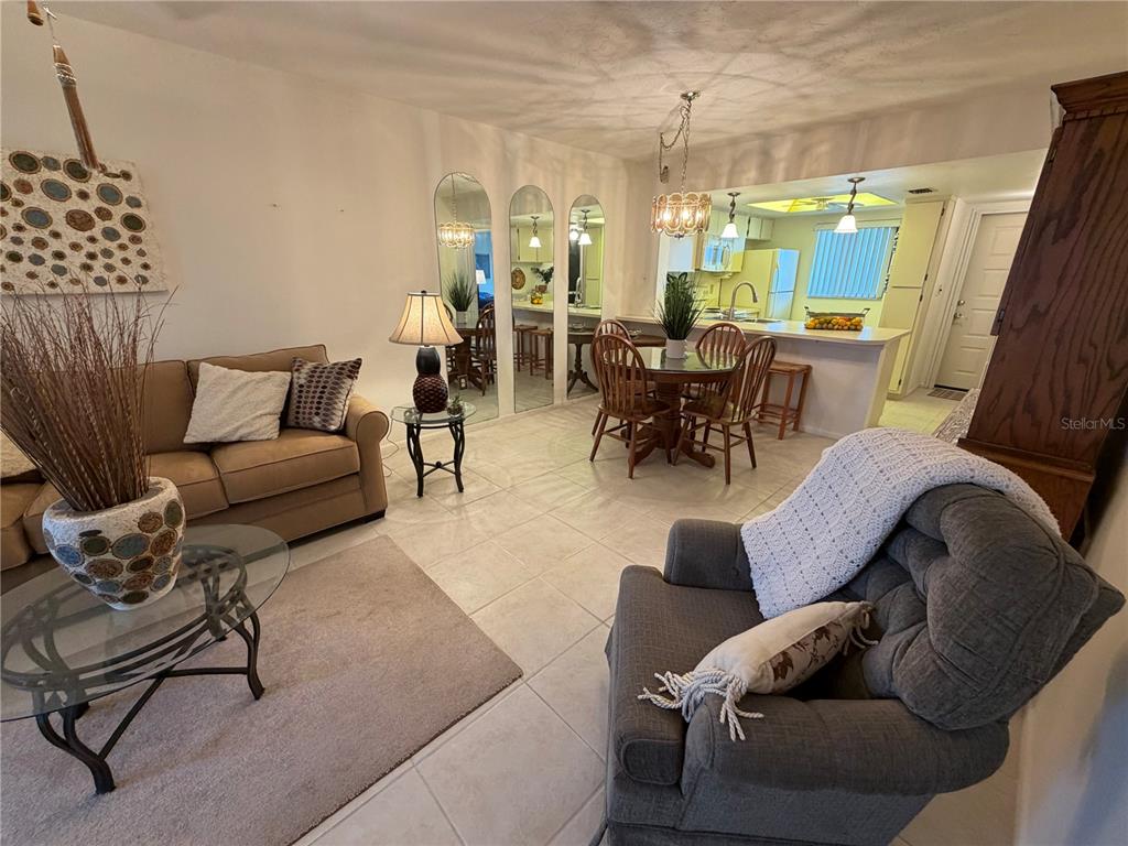 A living room and dining area feature tile floors, a sofa, and a kitchen view — 25225 RAMPART BOULEVARD UNIT 2203, PUNTA GORDA, FL