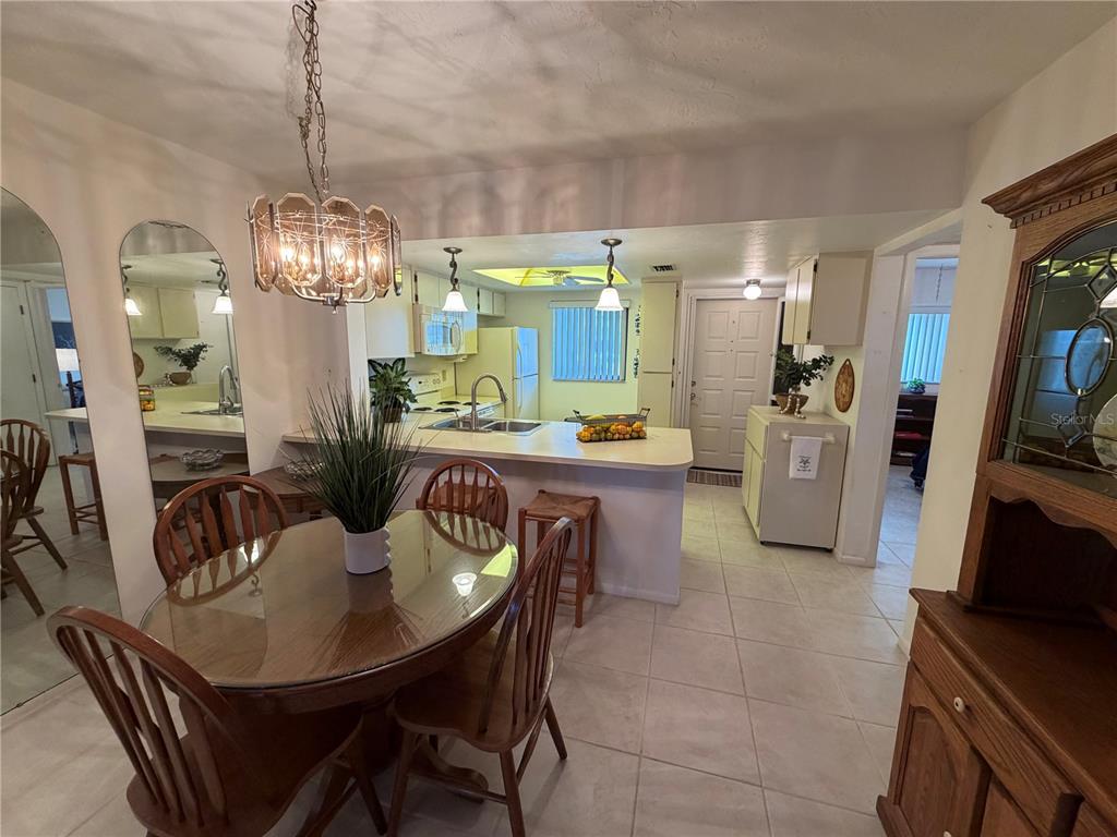 A dining area with a glass table opens to a kitchen featuring white cabinets — 25225 RAMPART BOULEVARD UNIT 2203, PUNTA GORDA, FL