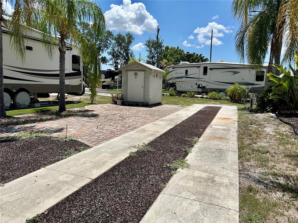 A paved patio and driveway area sit between two parked recreational vehicles and a shed — 2928 BIRDIE DRIVE, BOWLING GREEN, FL