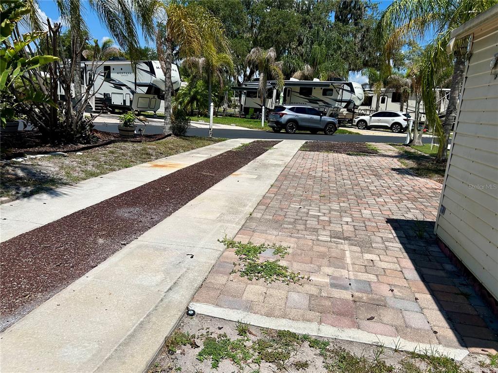 A paved driveway with a brick section and a gravel strip leads toward parked RVs — 2928 BIRDIE DRIVE, BOWLING GREEN, FL