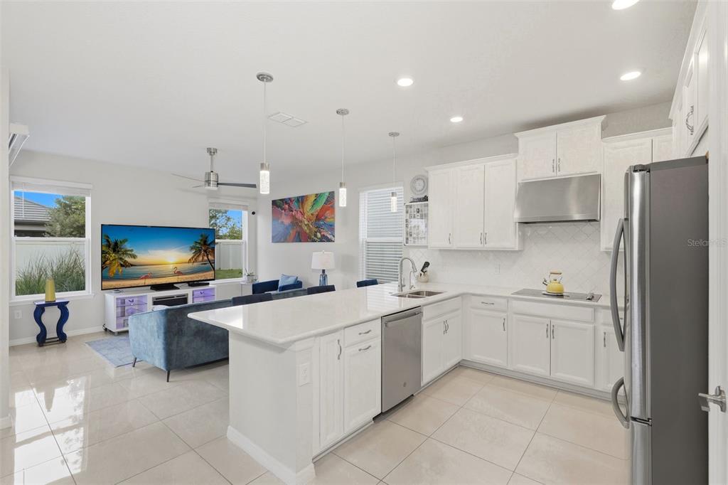 A modern open-concept kitchen with white cabinets, quartz countertops, and an adjacent living area — 1418 LONE FEATHER TRAIL, WINTER PARK, FL
