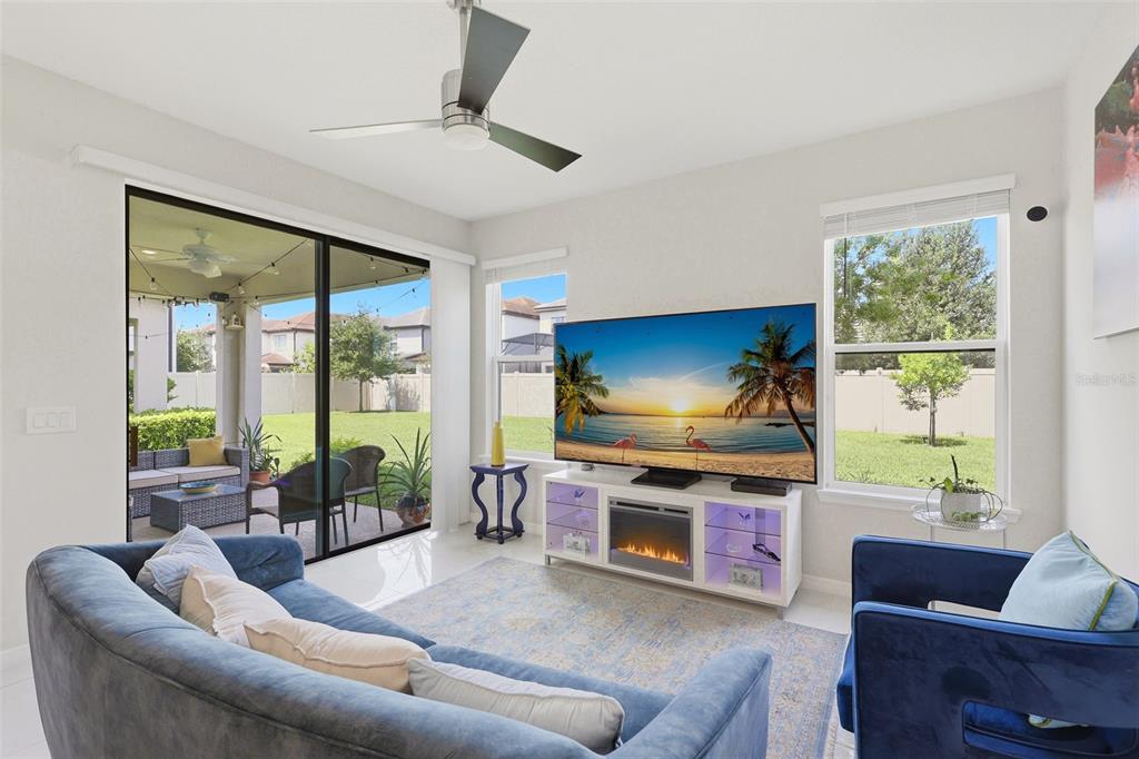 A living room with a blue sofa, a television on a fireplace console, and sliding doors — 1418 LONE FEATHER TRAIL, WINTER PARK, FL