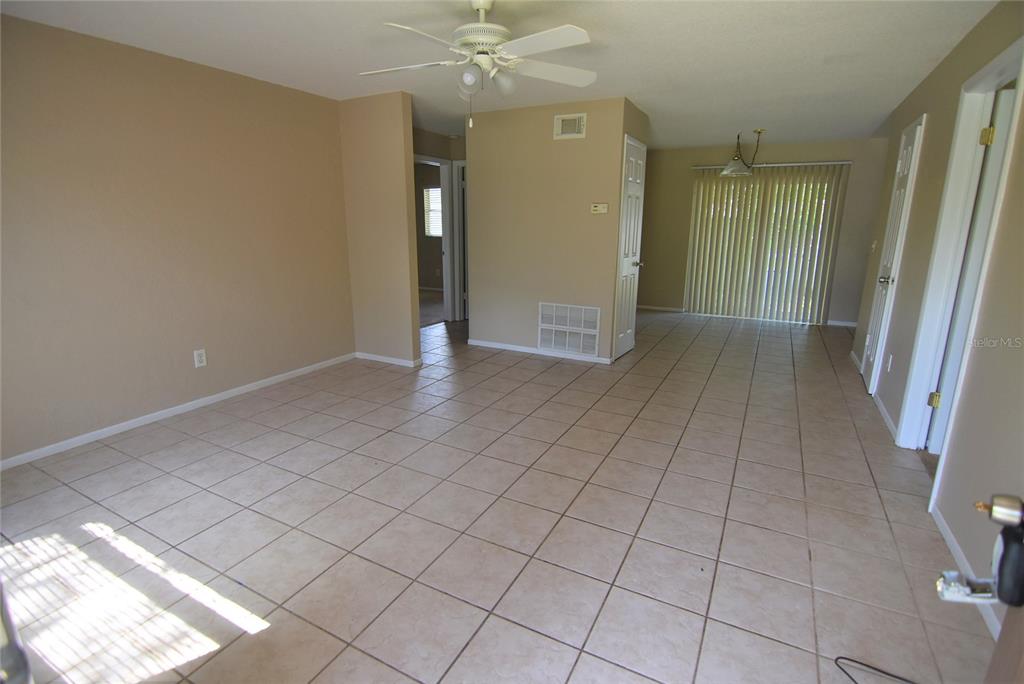 An open-concept living and dining area features beige tile flooring and a ceiling fan — 423 LONGWOOD CIRCLE, LONGWOOD, FL