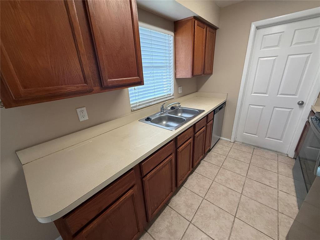 A kitchen features wood cabinets, a double-basin sink, light countertops, and tiled flooring — 423 LONGWOOD CIRCLE, LONGWOOD, FL