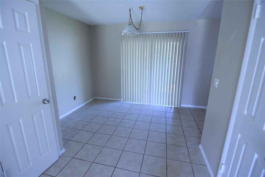 A dining area features beige tile flooring, a hanging light fixture, and vertical window blinds — 423 LONGWOOD CIRCLE, LONGWOOD, FL