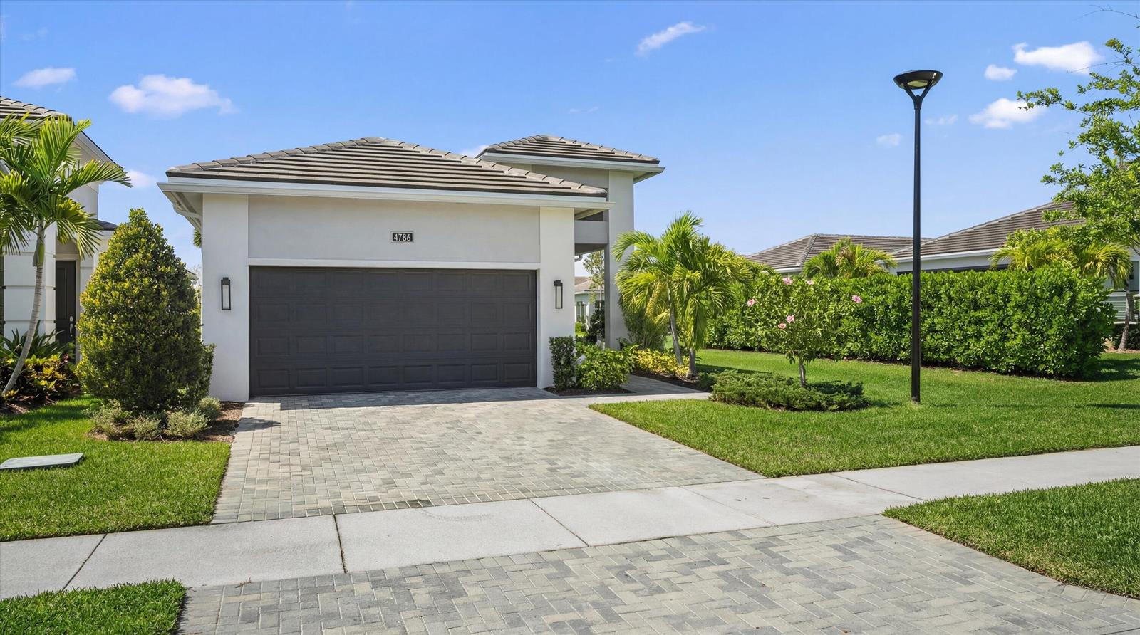 A single-story house with a gray garage door, paved driveway, and manicured landscaping — 4786 Saint Armands Way, Westlake FL 33470, WESTLAKE, FL
