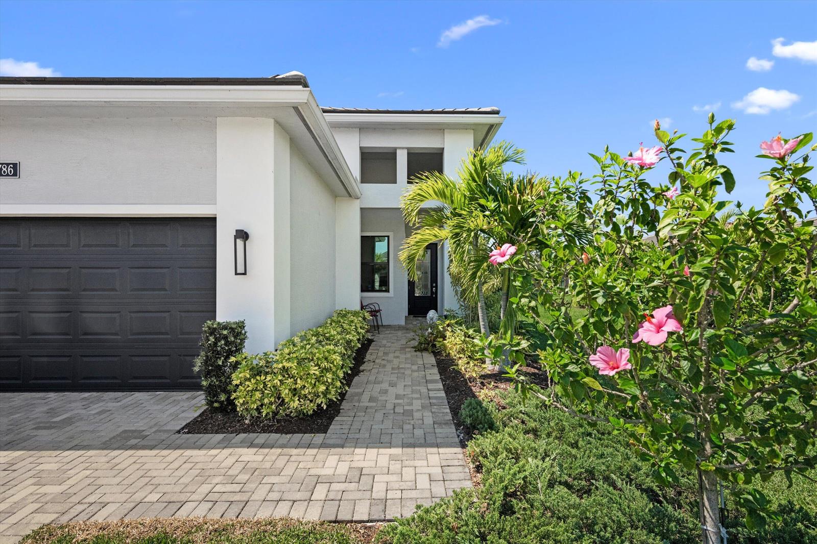 A paved walkway leads to the front entrance of a modern white house with a garage — 4786 Saint Armands Way, Westlake FL 33470, WESTLAKE, FL