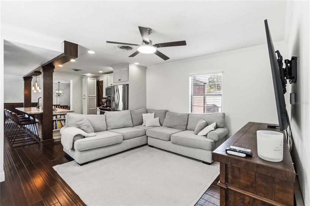 A living room with a gray sectional sofa, hardwood floors, and an open kitchen area — 2918 CARL TERRACE, ORLANDO, FL