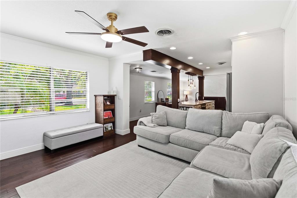 A living room with a large sectional sofa, dark wood floors, and an open kitchen — 2918 CARL TERRACE, ORLANDO, FL