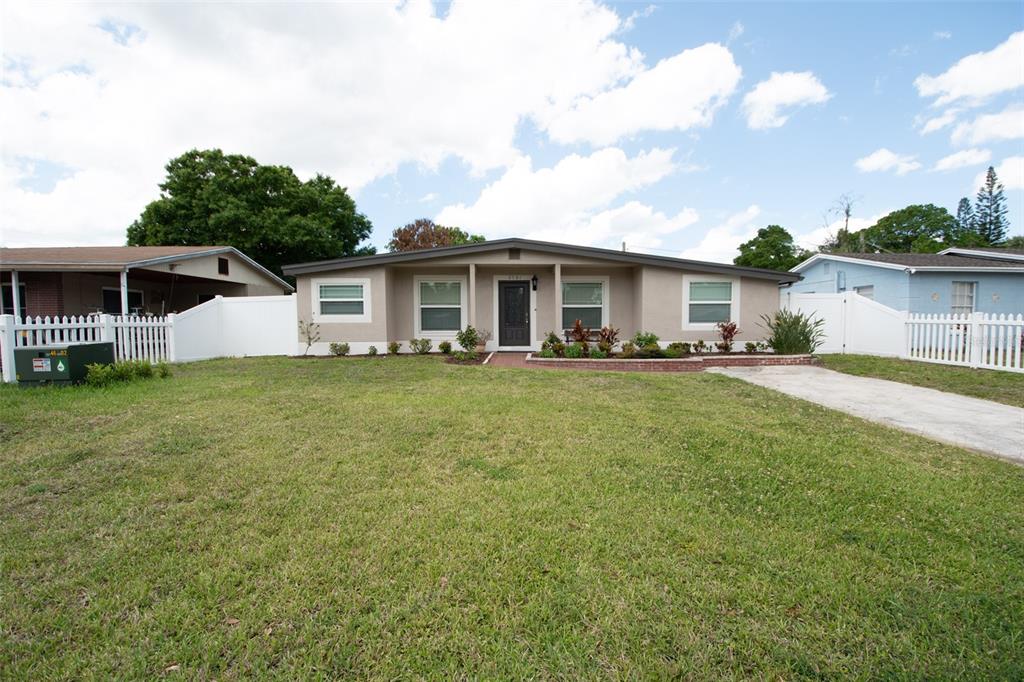 A single-story house with a beige exterior, a dark front door, and a white fence — 2701 CALLE STREET, TAMPA, FL