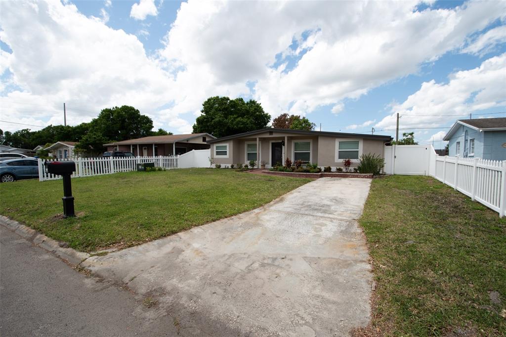 A single-story house with a concrete driveway and white picket fencing sits under a sky — 2701 CALLE STREET, TAMPA, FL