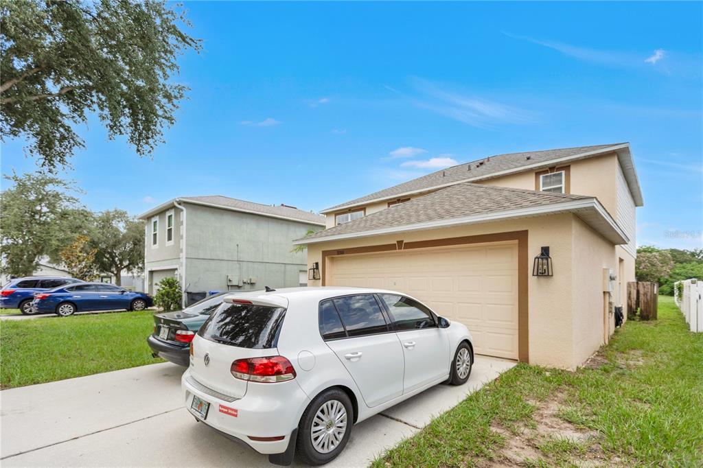 A two-story house with a beige stucco exterior and a white car parked in the driveway — 10304 RIVER BREAM DRIVE, RIVERVIEW, FL