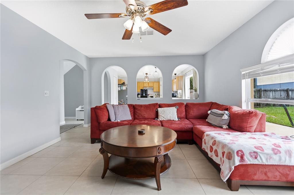 A living room features a large red sectional sofa, a round wooden table, and arched cutouts — 10304 RIVER BREAM DRIVE, RIVERVIEW, FL