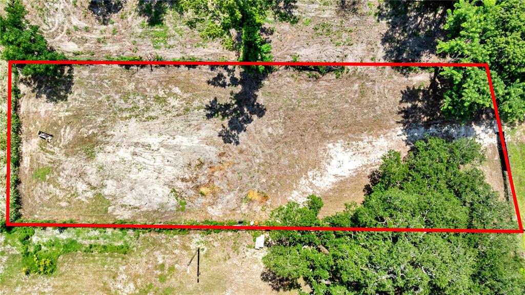 An aerial view shows a rectangular, cleared lot of land surrounded by trees and vegetation — 9924 ROCKHILL ROAD, THONOTOSASSA, FL
