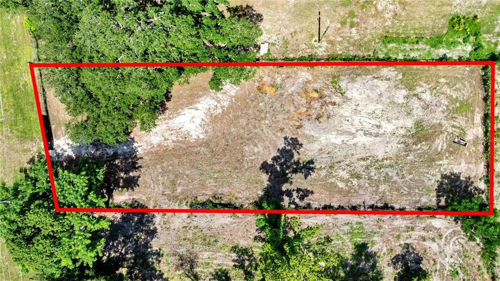 An aerial view shows a rectangular, cleared lot of land surrounded by trees — 9924 ROCKHILL ROAD, THONOTOSASSA, FL