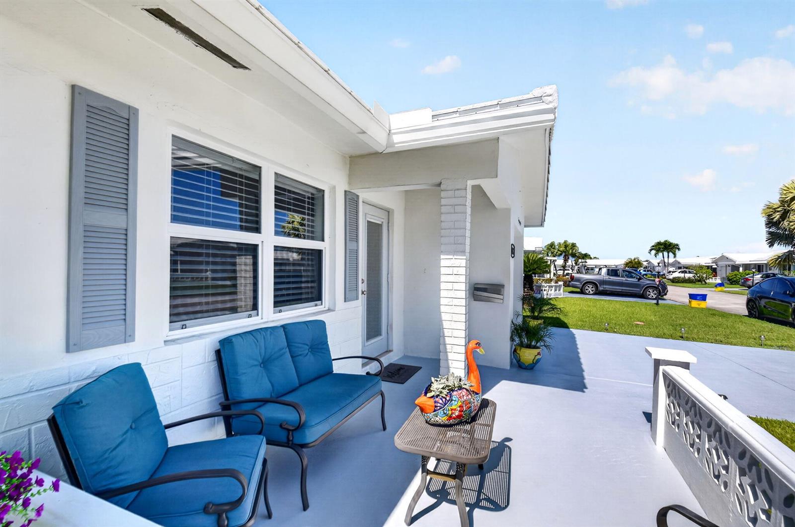 A white house exterior features a blue-cushioned patio set on a gray concrete porch — 2088 SW 13th Terrace, Boynton Beach FL 33426, BOYNTON BEACH, FL