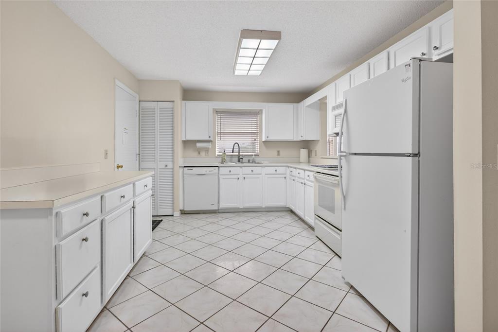 A kitchen with white cabinets, white appliances, and light-colored tile flooring set on a diagonal — 9077 SW 91ST CIRCLE, OCALA, FL