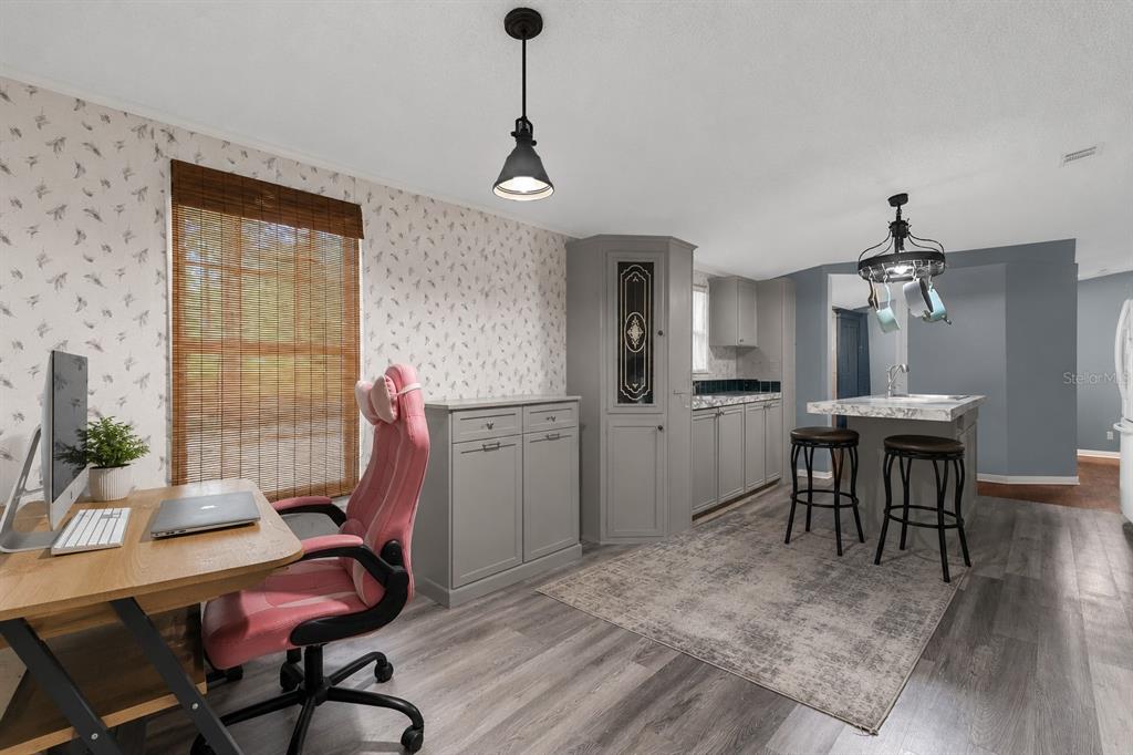 A room featuring a desk, a pink chair, grey cabinetry, and a kitchen island — 1705 SE 179 PLACE, SUMMERFIELD, FL