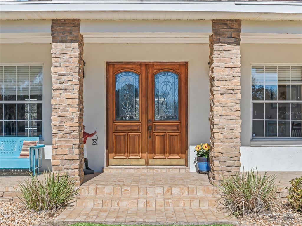 A front porch features stone pillars, a tiled stoop, and double wooden entry doors — 3030 NW 95TH AVENUE ROAD, OCALA, FL