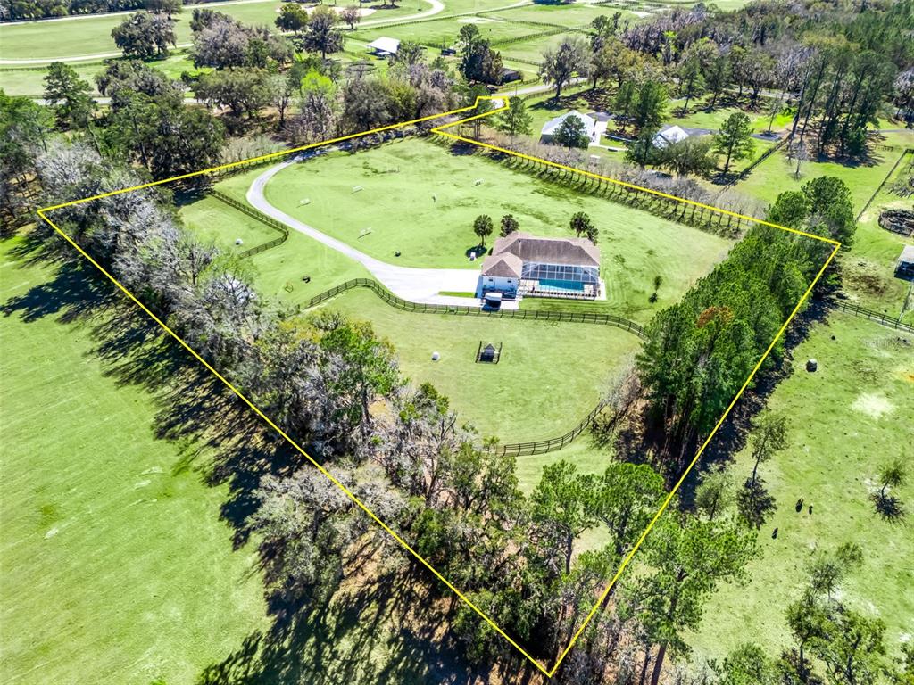 An aerial view shows a house with a pool inside a fenced, tree-lined property — 3030 NW 95TH AVENUE ROAD, OCALA, FL