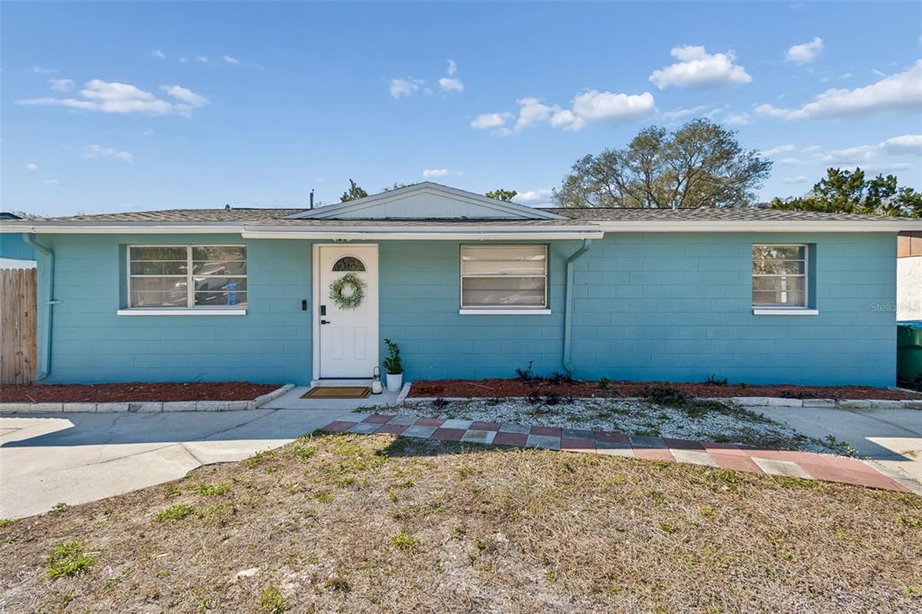 A single-story house with blue concrete block walls, a white front door, and a walkway — 13264 120TH LANE, LARGO, FL