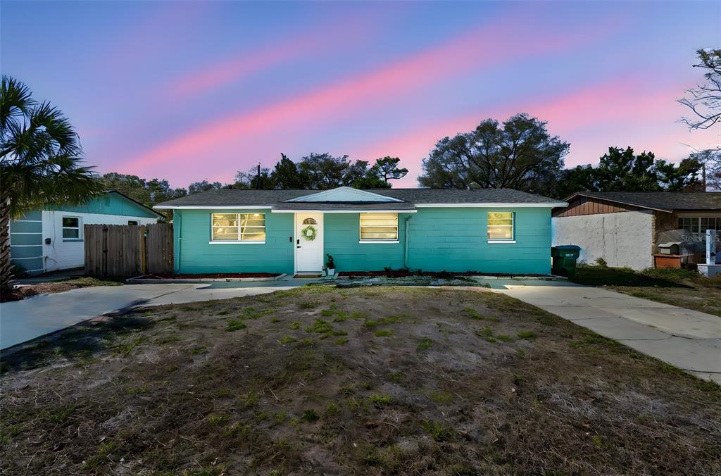 A teal, single-story house with a white front door and a concrete driveway at dusk — 13264 120TH LANE, LARGO, FL
