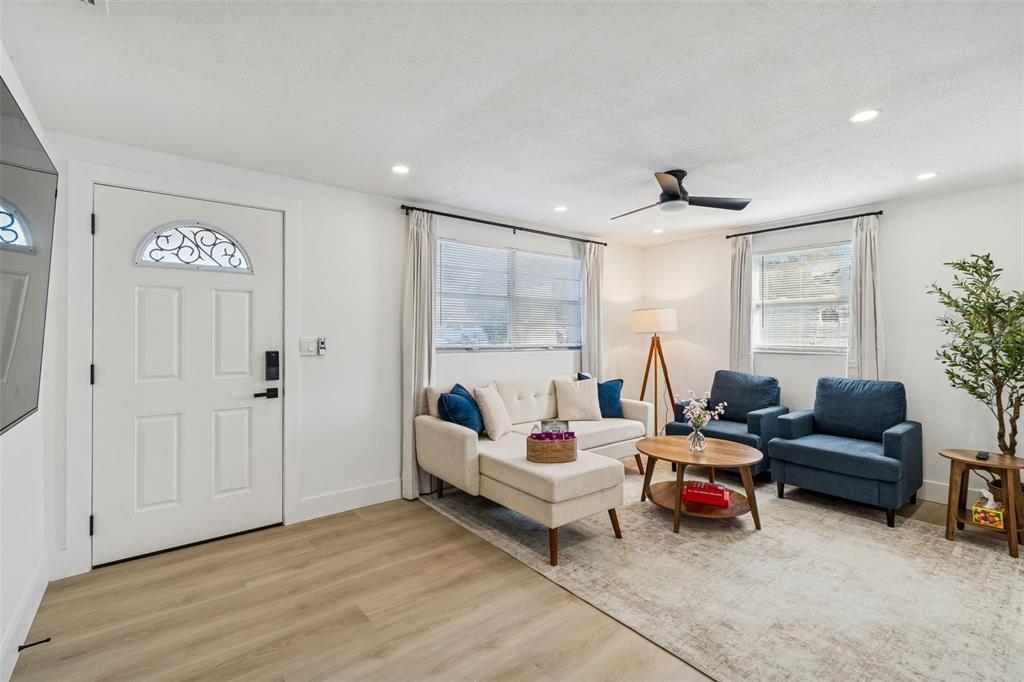 A living room features light wood flooring, a white sectional sofa, and two blue armchairs — 13264 120TH LANE, LARGO, FL