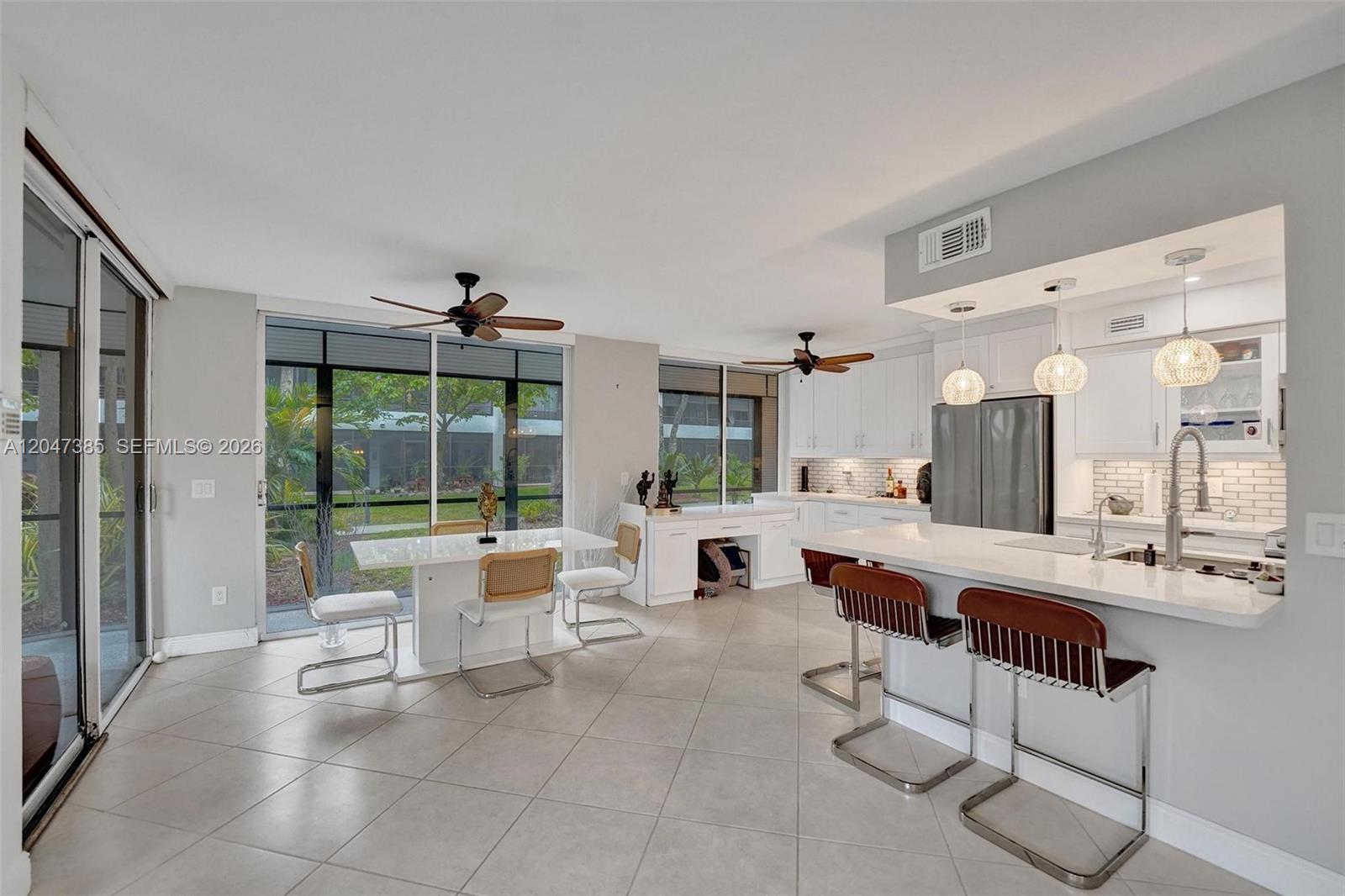 A bright open-concept kitchen and dining area with white cabinetry, tile floors, and sliding doors — 1430 Sheridan St # 1G, Hollywood FL 33020, HOLLYWOOD, FL