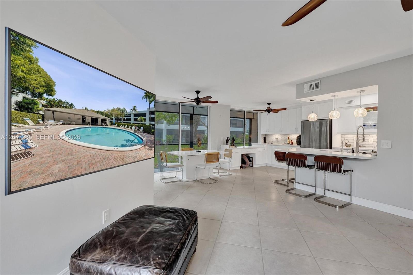 An open-concept living and dining area features a kitchen with bar seating and tile flooring — 1430 Sheridan St # 1G, Hollywood FL 33020, HOLLYWOOD, FL
