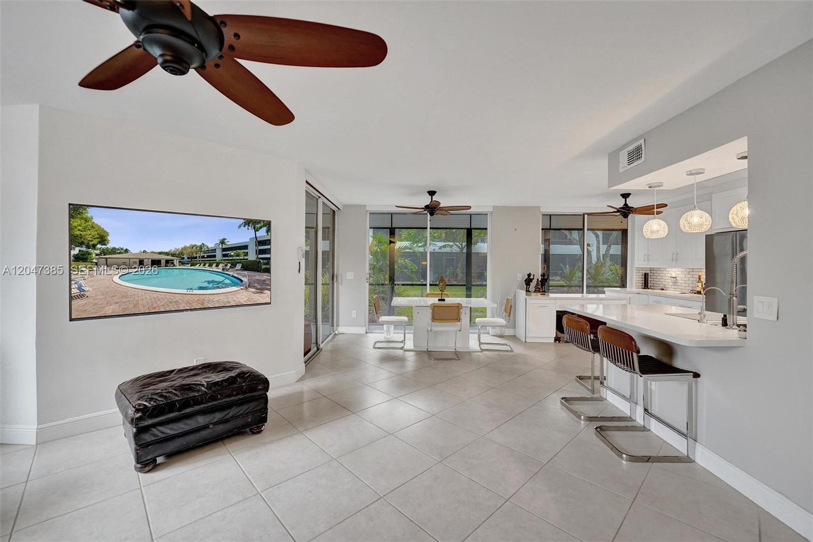 An open-concept living and dining area features tile floors, a kitchen island, and ceiling fans — 1430 Sheridan St # 1G, Hollywood FL 33020, HOLLYWOOD, FL