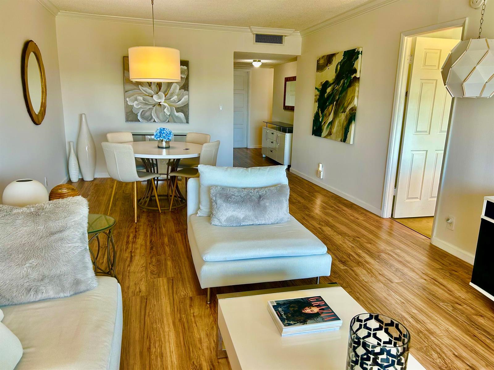 A living and dining area features light wood flooring, white furniture, and modern wall art — 3100 N Palm Aire Drive # 706, Pompano Beach FL 33069, POMPANO BEACH, FL