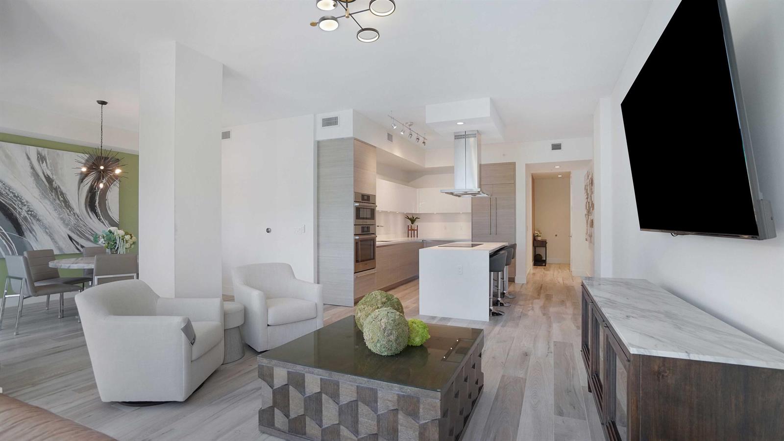 A modern open-concept living room and kitchen featuring light wood floors and white cabinetry — 155 E Boca Raton Road # 301, Boca Raton FL 33432, BOCA RATON, FL