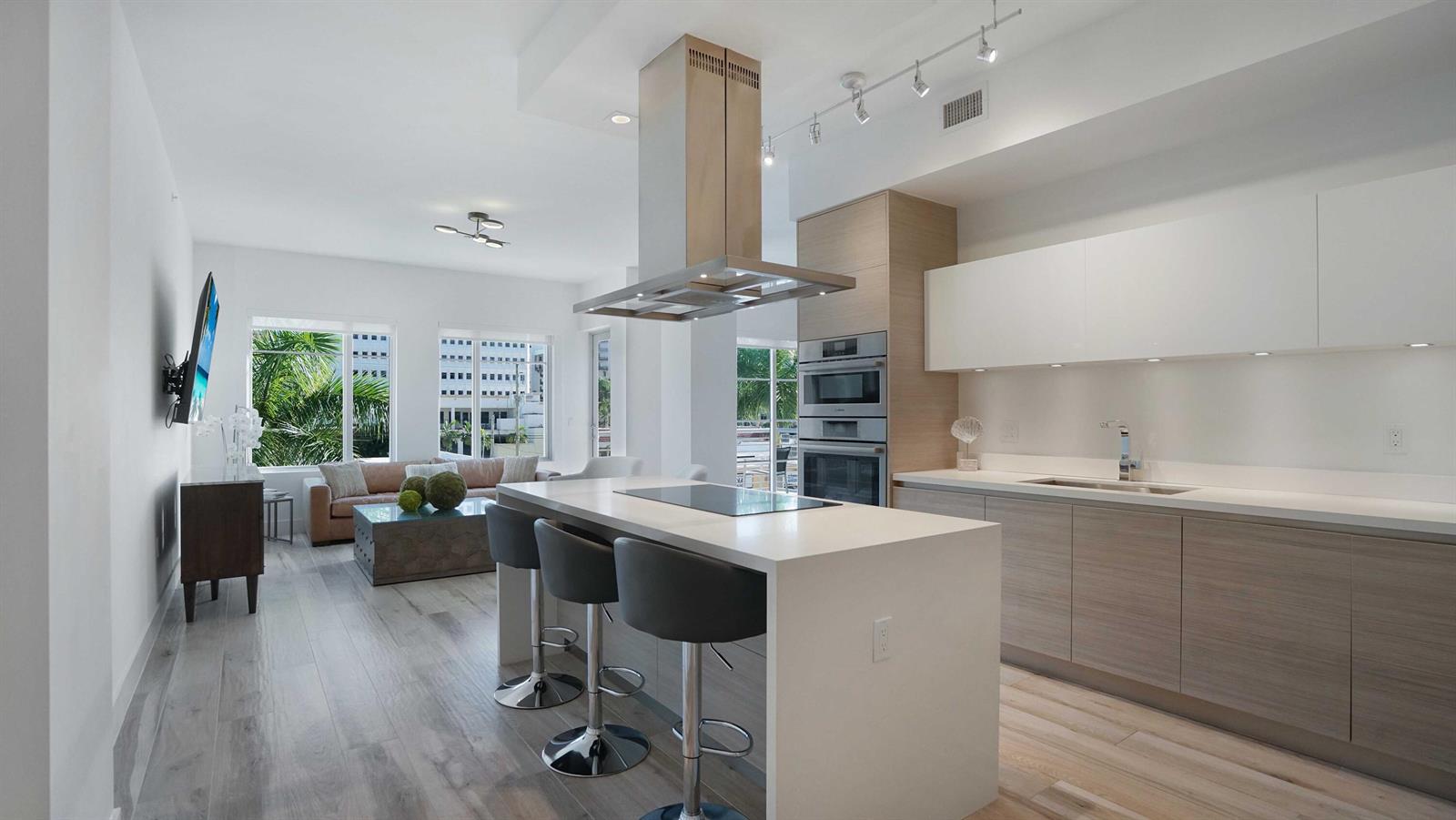 A modern kitchen with a central island and stainless steel appliances opens to a living area — 155 E Boca Raton Road # 301, Boca Raton FL 33432, BOCA RATON, FL